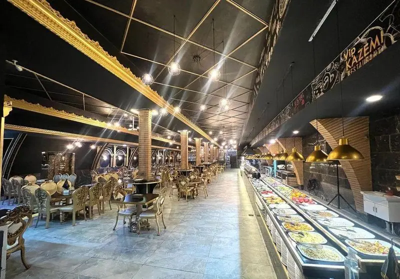 نمای داخلی رستوران وی آی پی کاظمی با بوفه سلف سرویس غذاهای متنوع و میز و صندلی‌های مجلل در فضایی لوکس و مدرن.