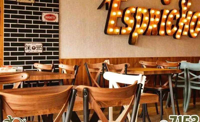 فضای داخلی فست فود 007 با دکوراسیون مدرن چوبی، میز و صندلی‌های شیک، دیوار آجری و تابلوی نورانی جذاب.