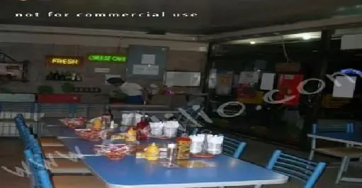 نمای داخلی پیتزا آرد با میز و صندلی های آبی، آماده پذیرایی مشتریان. محیطی دوستانه برای صرف پیتزا و غذاهای تازه و متنوع.