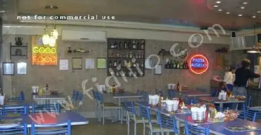 فضای داخلی دنج و مدرن رستوران پیتزا آرد، شامل میز و صندلی‌های آبی، دکوراسیون دیوار و تابلوهای نئونی روشن.