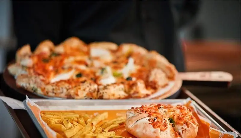 سرویس دهی پیتزای تازه و خوشمزه به همراه سیب زمینی سرخ کرده در پیتزایی زیگ زاگ. پیتزایی با طراحی خاص و غذای لذیذ آماده برای مشتریان.