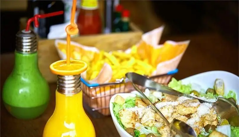 وعده غذایی جذاب در پیتزایی زیگ زاگ: نوشیدنی‌های میوه‌ای در بطری‌های خاص، سیب‌زمینی سرخ‌کرده و سالاد تازه با سس و پنیر.