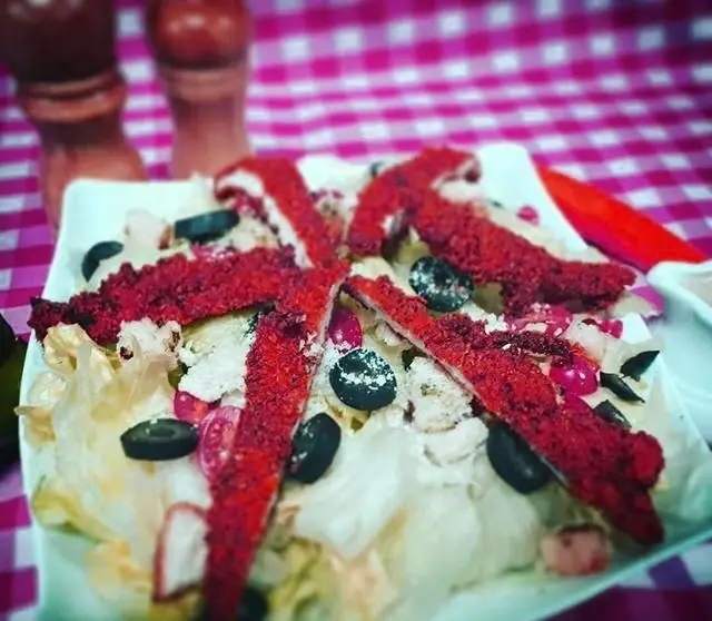 سالاد تازه و رنگارنگ رستوران ایتالیایی اسی فود با استریپس مرغ سوخاری قرمز و زیتون، غذایی اشتهاآور و سالم.