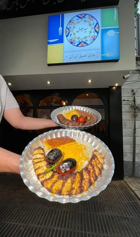 چلوکباب‌های دلپذیر و باکیفیت کترینگ سید جلال همراه با برنج زعفرانی، ته دیگ طلایی و گوجه کبابی، بهترین غذای اصیل ایرانی.