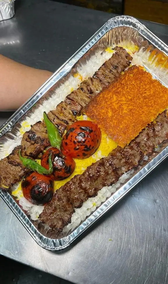 چلوکباب کوبیده و برگ با برنج زعفرانی، گوجه کبابی و فلفل از کترینگ سید جلال. غذای ایرانی بیرون بر در ظرف آلومینیومی.