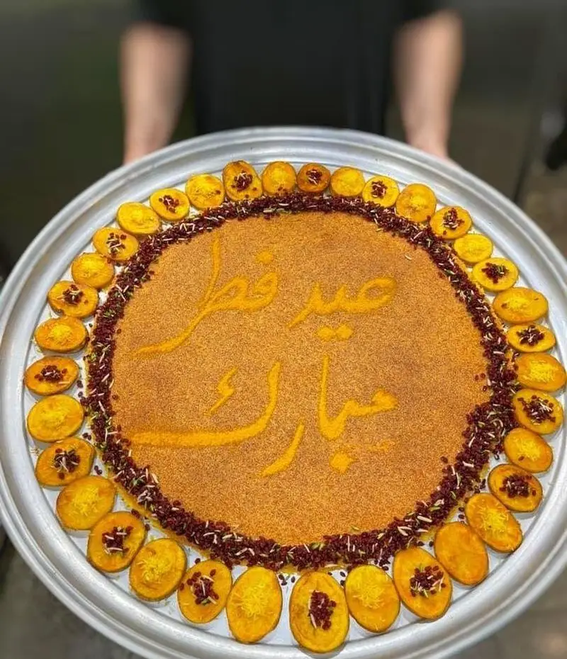 سینی بزرگ و زیبای پلو زعفرانی با نوشته "عید فطر مبارک"، مزین به زرشک و ته دیگ، اثری هنری از رستوران شمشیری.