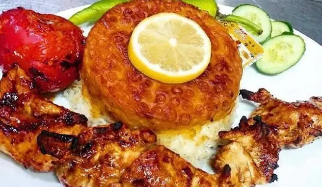 جوجه کباب آبدار و برنج زعفرانی با ته دیگ طلایی رستوران خوتکا، همراه گوجه کبابی و سبزیجات تازه، غذای اصیل ایرانی.