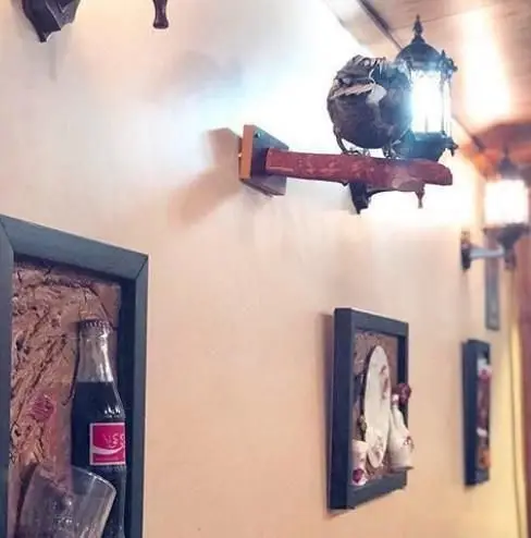 دکوراسیون داخلی دلنشین رستوران ایرانی خوتکا، با فانوس‌های سنتی، قاب‌های هنری حاوی بطری و ظروف تزئینی روی دیوار.