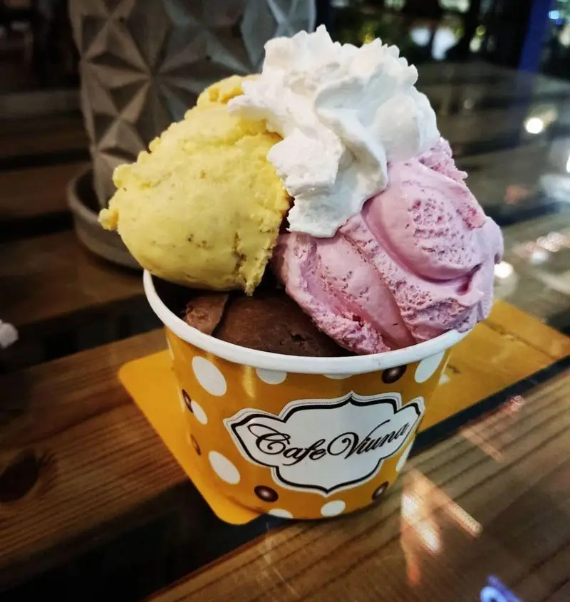 بستنی سه اسکوپ رنگارنگ و خوشمزه (میوه‌ای، شکلاتی) با خامه فراوان در کافه رستوران ویونا پلاس، دسری خنک و لذیذ.