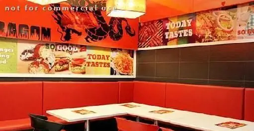 فضای داخلی مدرن فست فود دراگون با دکوراسیون جذاب قرمز و مشکی، میزهای سفید و صندلی‌های راحت. نمایش غذاهای خوشمزه و طراحی اژدها بر روی دیوارها.