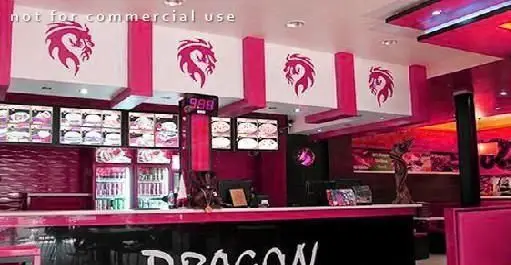 نمای داخلی پر جنب و جوش فست فود دراگون با تم رنگی صورتی و مشکی، لوگوهای اژدها، منوهای دیجیتال و کانتر سفارش.