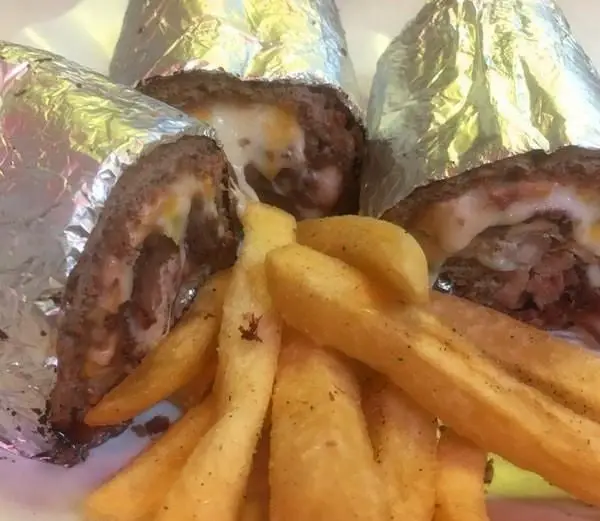 عکس از غذاهای لذیذ فست فود دراگون شامل رول‌های گوشت و پنیر آب شده، همراه با سیب‌زمینی سرخ کرده تازه و خوشمزه. تجربه طعمی عالی.