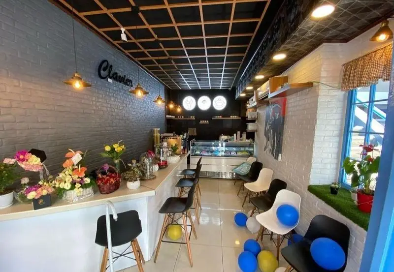 نمای داخلی شیک کافه بستنی ایتالیایی کلاویه با دکوراسیون مدرن، پیشخوان پر از گل، صندلی‌های بار، یخچال بستنی و دیوار آجری.