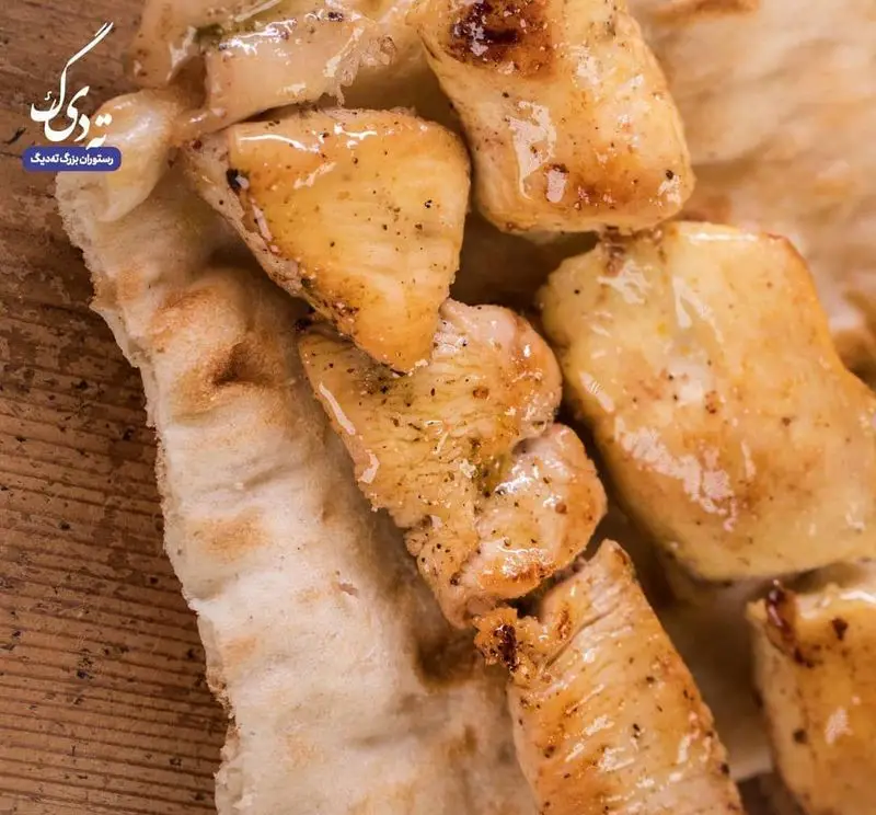 تکه‌های جوجه کباب طلایی و آبدار روی نان داغ، نمادی از غذای خوشمزه و با کیفیت در رستوران ته دیگ. تجربه‌ای لذت‌بخش از چلو کباب.