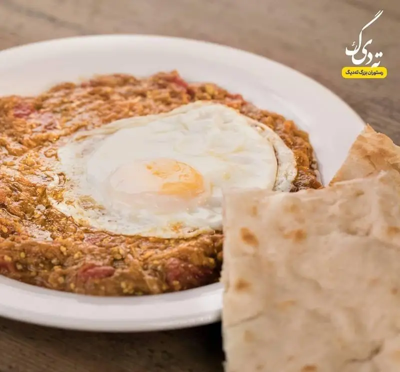 غذای سنتی ایرانی شامل املت تخم مرغ و میرزا قاسمی با نان تازه، بهترین صبحانه در رستوران ته دیگ برای تجربه‌ای اصیل.