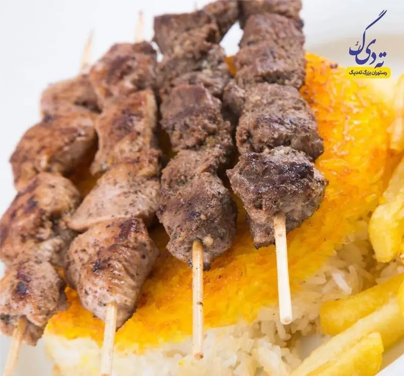 رستوران ته دیگ: سیخ‌های کباب گوشت و جوجه کباب ایرانی بر روی پلو با ته دیگ زعفرانی طلایی و سیب‌زمینی سرخ کرده.