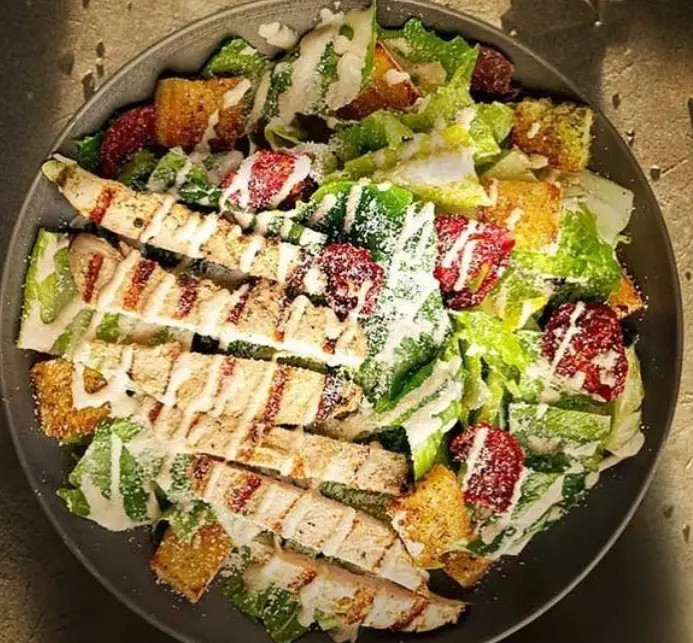 سالاد سزار مرغ گریل خوشمزه کافه اودسا، شامل سینه مرغ گریل، کاهو، کروتون، توت فرنگی و سس مخصوص با پنیر پارمزان.