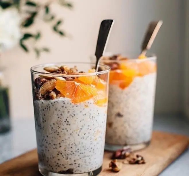 دو لیوان پارفه چیا با پرتقال تازه و گرانولا، دسر یا صبحانه سالم و خوشمزه از کافه اودسا. ایده‌آل برای شروع یک روز پرانرژی.