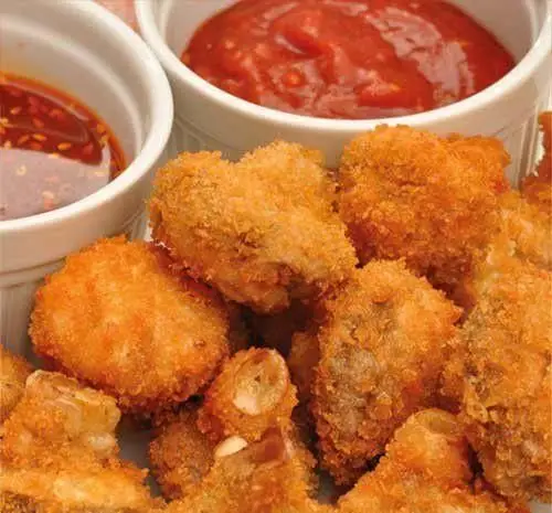 پاپ کورن مرغ کنتاکی طلایی و کریسپی، آماده سرو با سس های کچاپ و سس تند. بهترین تجربه فست فود و غذای خوشمزه!