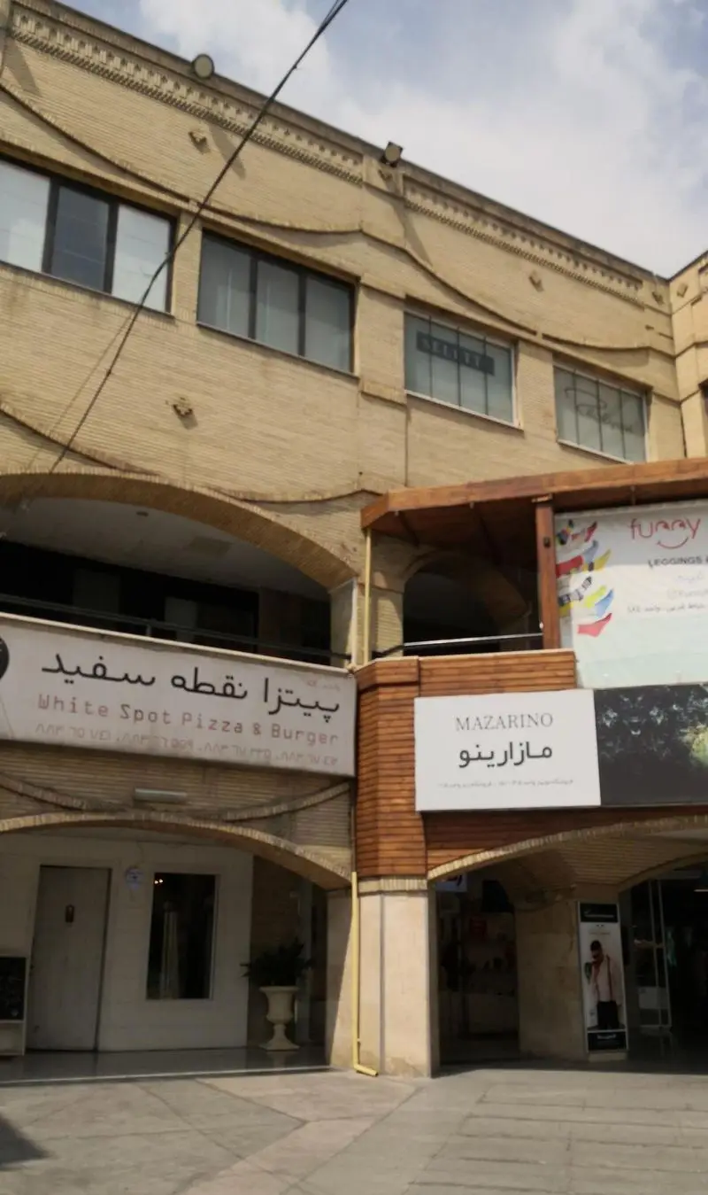 نمایی از کافه رستوران نقطه سفید (White Spot Pizza & Burger) با ورودی آجری و قوس‌دار، ارائه دهنده پیتزا و برگر.