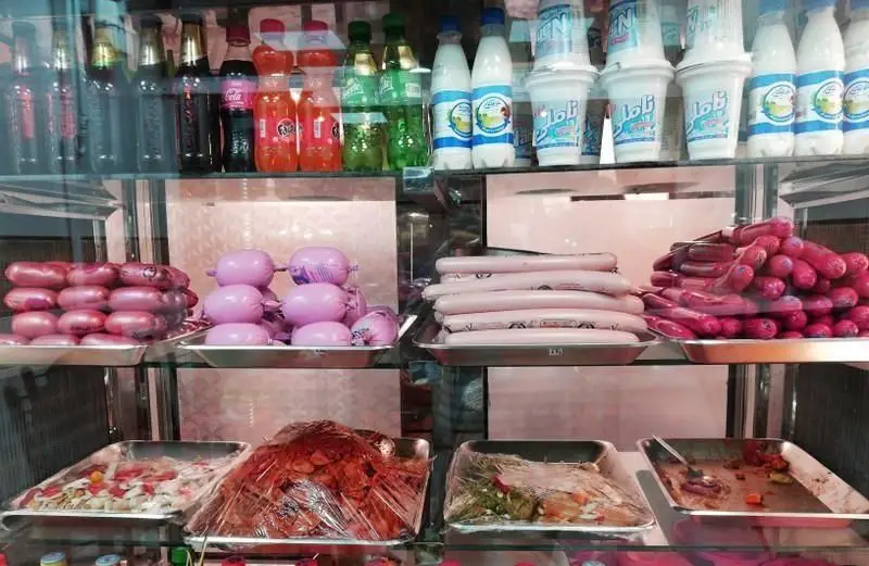 نمایی از یخچال ساندویچی چیتا شامل انواع سوسیس، کالباس، مخلفات ساندویچ و نوشیدنی‌هایی مانند دوغ، فانتای پرتقالی، کوکا و اسپرایت