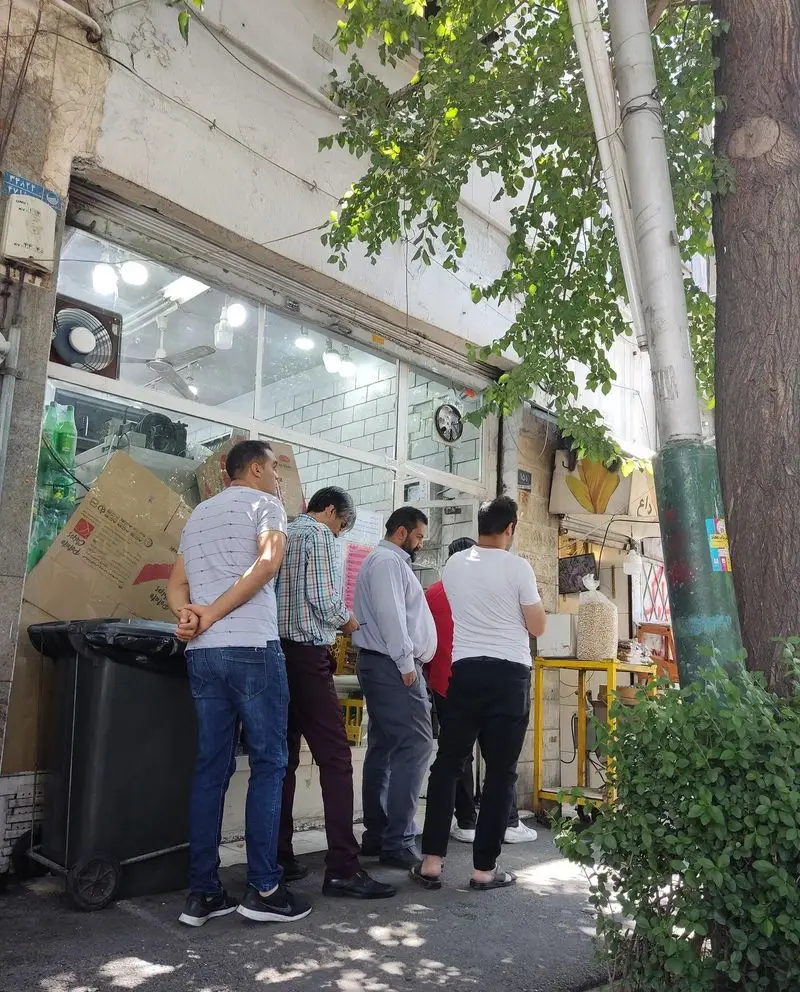 مشتریان در حال انتظار جلوی مغازه ساندویچ موسیو، نشان دهنده استقبال و محبوبیت این کسب و کار در فضای شهری.