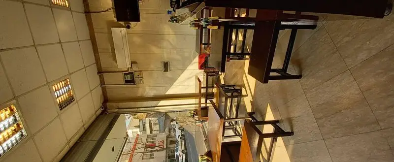 تصویر فضای داخلی رستوران گردسوز با میز و صندلی‌های چوبی مدرن، نورگیر بزرگ، کفپوش زیبا و محیطی دلنشین برای مشتریان.