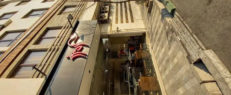 نمای بیرونی و بالای رستوران گردسوز با تابلوی زیبای قرمز رنگ، ورودی شیشه‌ای و جزئیات معماری مدرن ساختمان در یک روز آفتابی.