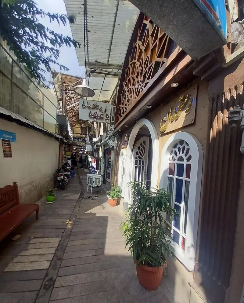 نمای دنج و سنتی رستوران باغچه محمد در یک کوچه قدیمی، با معماری زیبا، پنجره‌های رنگی و گلدان‌های طبیعی.