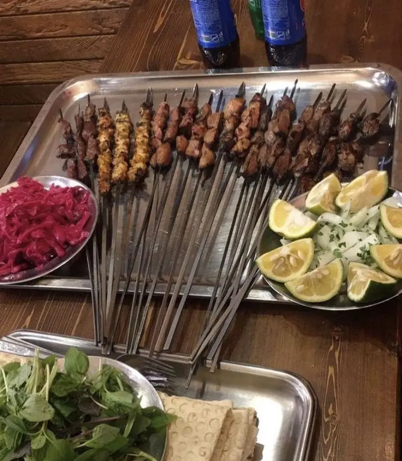 سینی کبابهای اصیل و داغ جگرکی دایی شامل جگر، دل، قلوه و جوجه، همراه با سبزی تازه، پیاز، لیمو و ترشی کلم برای یک تجربه غذایی فوقالعاده.