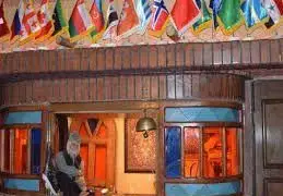 کافه رستوران سنتی سوته دلان با فضای داخلی چشم‌نواز و دکوراسیون اصیل چوبی، پرچم کشورهای مختلف و شیشه‌های رنگی دلپذیر.