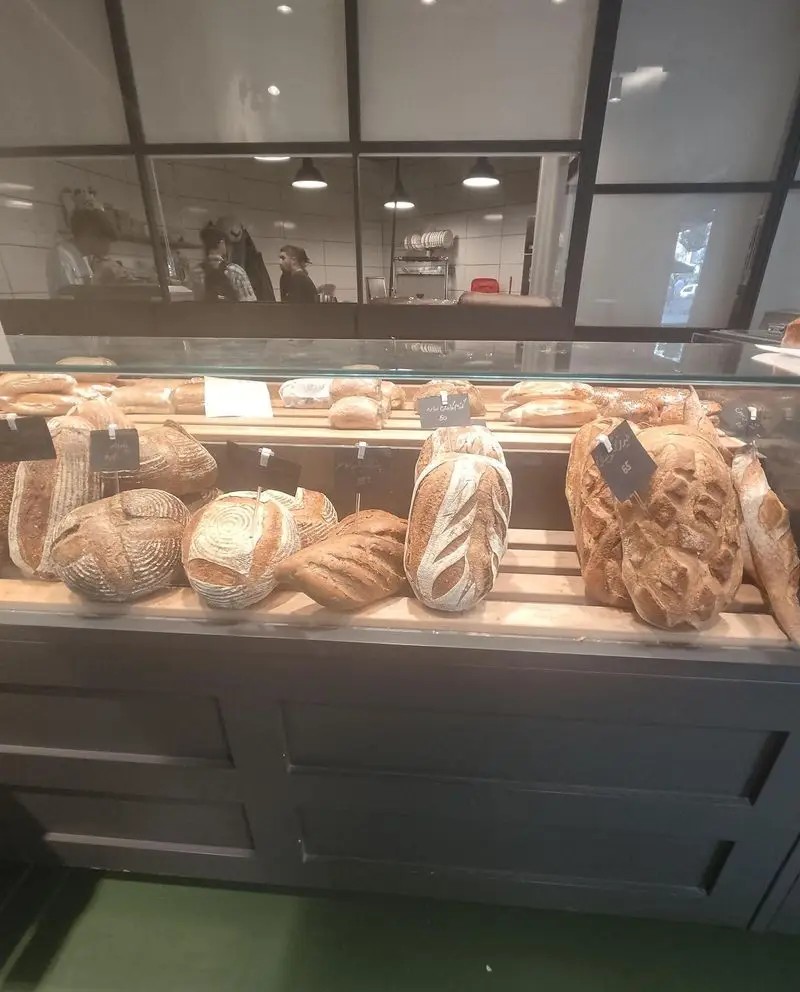 نمایی از ویترین جذاب کافه نانوایی دوبار با مجموعه‌ای بی‌نظیر از نان‌های تازه، دست‌ساز و سالم، از جمله نان‌های حجیم و artisan با کیفیت عالی.