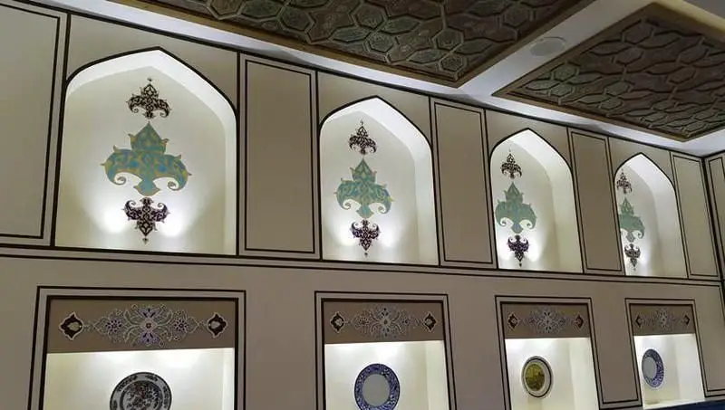 طراحی داخلی سنتی پنج دری با طاقچه‌های نورپردازی شده، نقش‌ونگارهای اصیل ایرانی، سقف کنده‌کاری و ظروف دکوری فاخر.