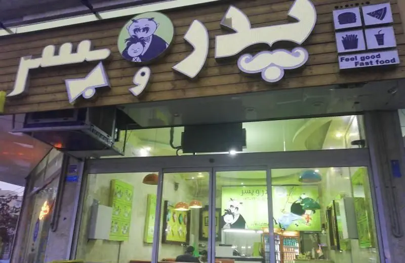 نمای بیرونی فست فود پدر و پسر با تابلوی اصلی، لوگوی پدر و پسر و نمادهای غذاهای سریع شامل همبرگر، پیتزا، سیب زمینی و نوشابه.