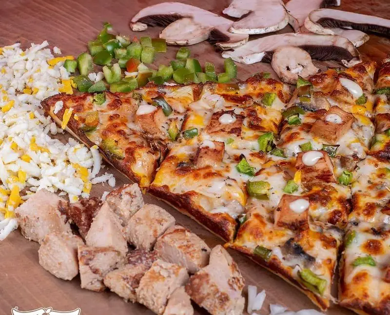 پیتزای مرغ و قارچ سیب ۳۶۰، برش‌خورده مربعی با فلفل دلمه و پنیر فراوان. مواد اولیه تازه شامل مرغ، قارچ، فلفل و پنیر در کنار آن.