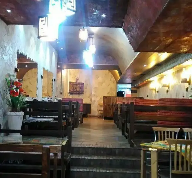 نمای داخلی کافه رستوران برج آزادی، فضایی دنج و سنتی با میز و صندلی چوبی، دیوارهای سنگی و نورپردازی گرم و جذاب.