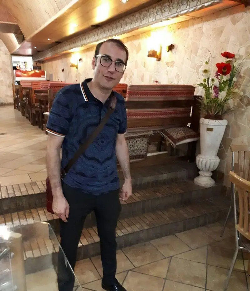 مردی خوش‌تیپ در فضای دنج و دلنشین کافه رستوران برج آزادی، با دکوراسیون سنتی و میز و صندلی‌های شیک.