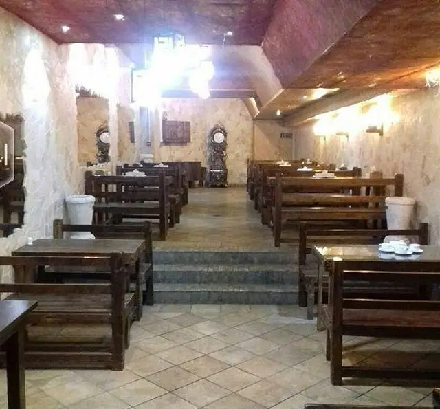 فضای داخلی کافه رستوران برج آزادی با دکوراسیون سنتی و چوبی، میز و صندلی‌های قهوه‌ای، دیوار سنگی و محیطی دلنشین.