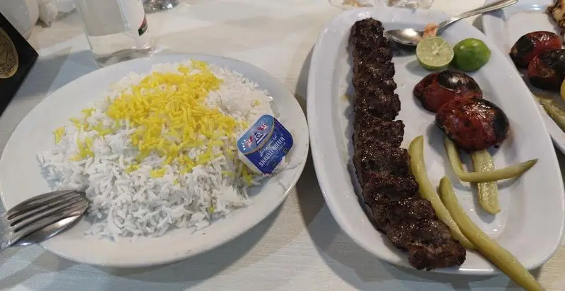 سفارش کباب کوبیده همراه با برنج زعفرانی، گوجه کبابی و چاشنی‌ها در رستوران افتخاری برای یک وعده غذای ایرانی لذیذ و دلنشین.
