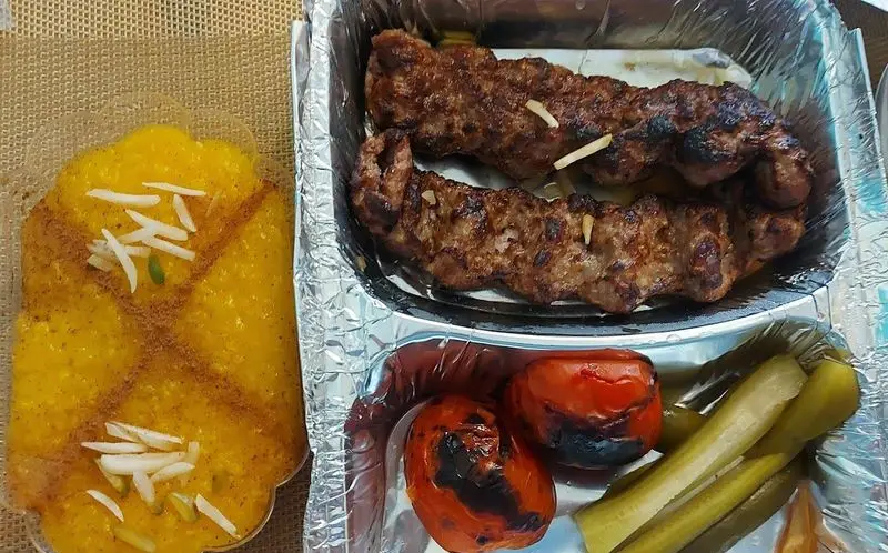 سفارش بیرون بر رستوران افتخاری: کباب کوبیده، گوجه کبابی، خیارشور و شله زرد زعفرانی. غذای ایرانی اصیل و لذیذ.