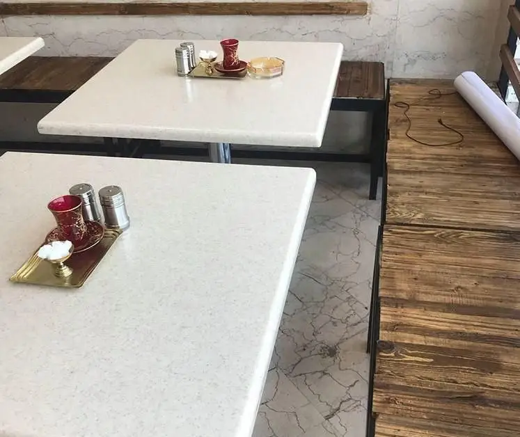 تصویری از فضای داخلی رستوران سنتی علاالدین با میزهای سفید، سینی‌های چای و نمکدان، و کفپوش‌های سنگی و چوبی.