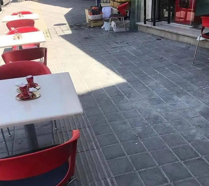 تصویری از فضای بیرونی رستوران سنتی علاالدین، با میز و صندلی‌های شیک قرمز و دو استکان چای ترکی روی میز. محیطی آرام و دعوت‌کننده.