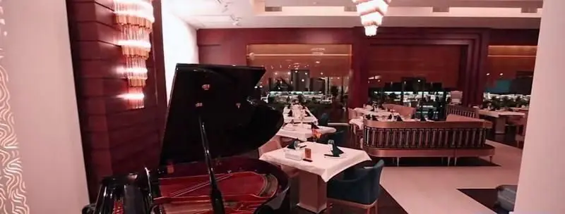 فضای داخلی لوکس رستوران ایرانی شاندیز ماهان رویال با پیانوی بزرگ، میزهای شیک چیده شده و نورپردازی گرم، آماده پذیرایی.