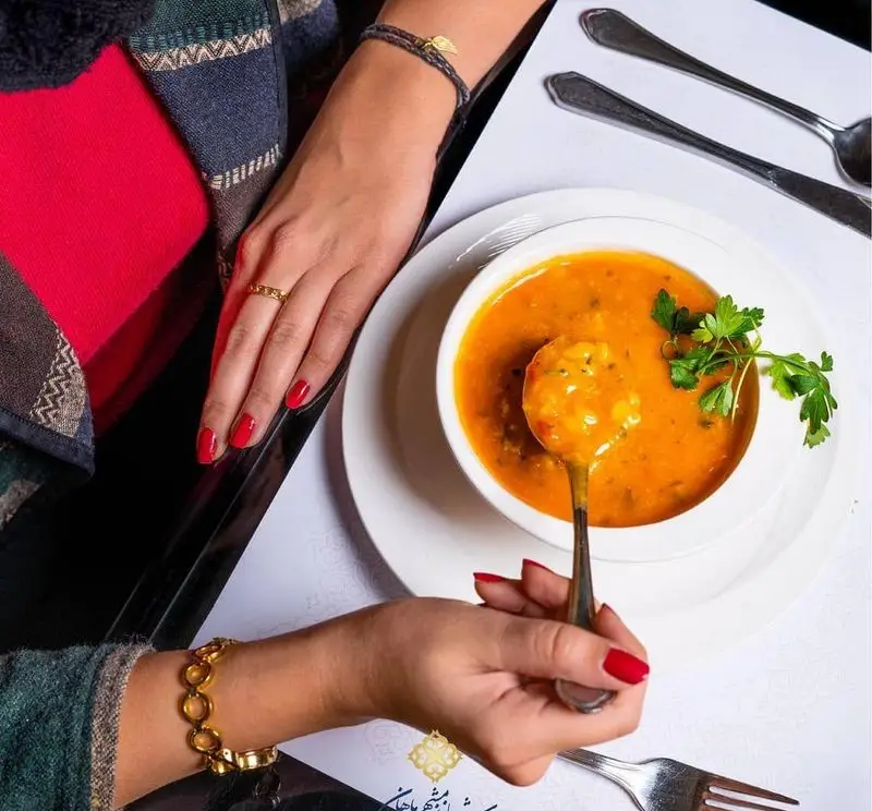 سوپ گرم و لذیذ روی میز رستوران ایرانی شاندیز ماهان رویال. پیش غذایی دلپذیر برای آغاز تجربه بی‌نظیر غذاهای اصیل ایرانی.