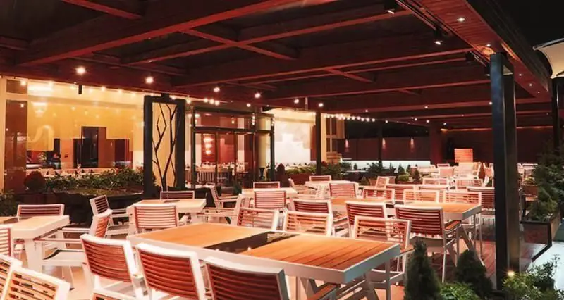 نمایی از فضای باز رستوران ایرانی شاندیز ماهان رویال با دکوراسیون مدرن، میز و صندلی‌های شیک و نورپردازی گرم در یک شب دلنشین