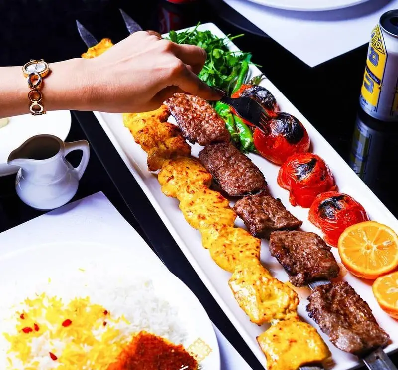 نمای نزدیک از انواع کباب خوشمزه ایرانی شامل جوجه کباب و کباب کوبیده در رستوران شاندیز ماهان رویال با برنج و مخلفات لذیذ.