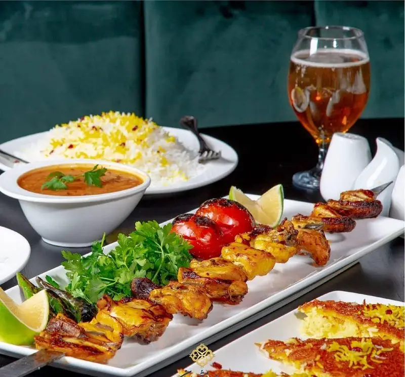 میز شام رستوران ایرانی شاندیز ماهان رویال با جوجه کباب، برنج زعفرانی، ته دیگ و خورشت لذیذ. بهترین غذای اصیل ایرانی.