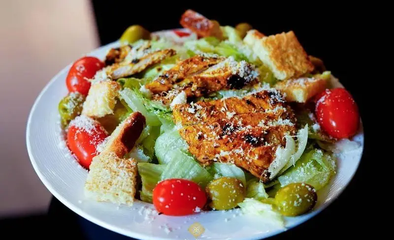 سالاد سزار مرغ گریل شده با کاهو، گوجه گیلاسی، زیتون، نان تست و پنیر پارمسان در رستوران ایرانی شاندیز ماهان رویال.
