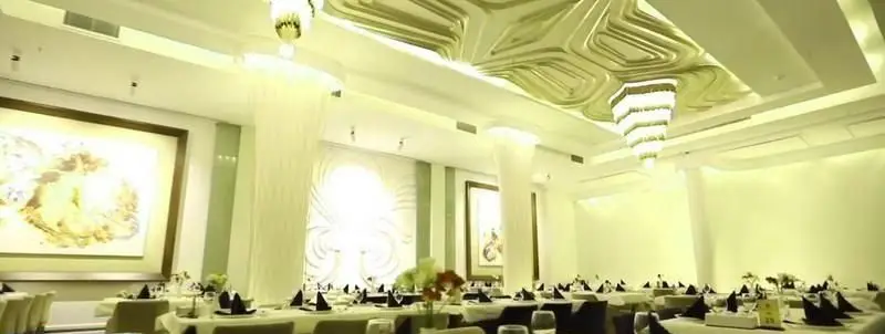 رستوران ایرانی شاندیز ماهان رویال: فضای داخلی لوکس و شیک برای پذیرایی، با میزآرایی زیبا، سقف دکوراتیو، لوسترهای مدرن و آثار هنری دیواری.