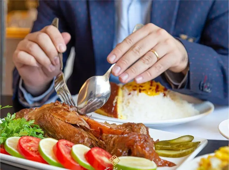 مشتری در رستوران شاندیز ماهان رویال در حال لذت بردن از خوراک گوشت لذیذ ایرانی همراه با پلو زعفرانی و ته دیگ خوشمزه.